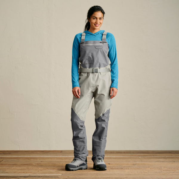 woman facing camera wearing grey waders and wading boots