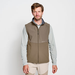 man smiling to camera wearing brown vest from Orvis in front of white abckground