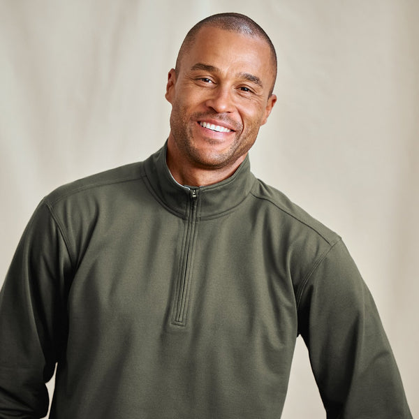 Man wearing a green pullover with a neutral background