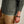 Load image into Gallery viewer, Person wearing a green sweatshirt with a small logo and beige pants, holding their arm.
