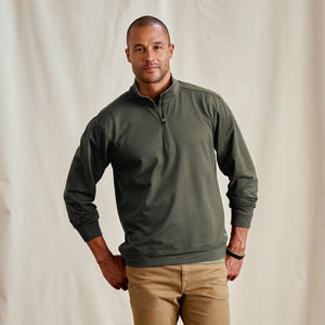 Man wearing a green pullover with a quarter zip against a beige background