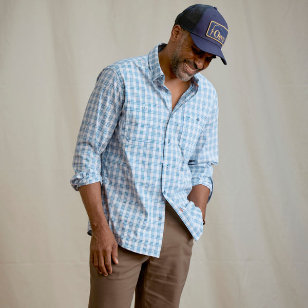 Man modelling dark blue cap, white and blue shirt and brown pants