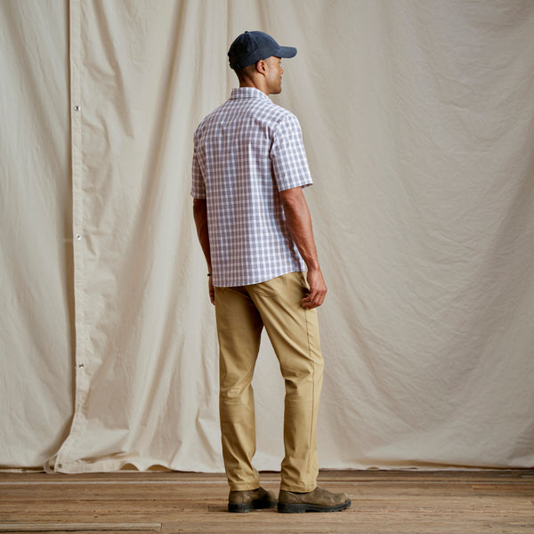 Man with his back to the camera wearing beige pants and short sleeved shirt