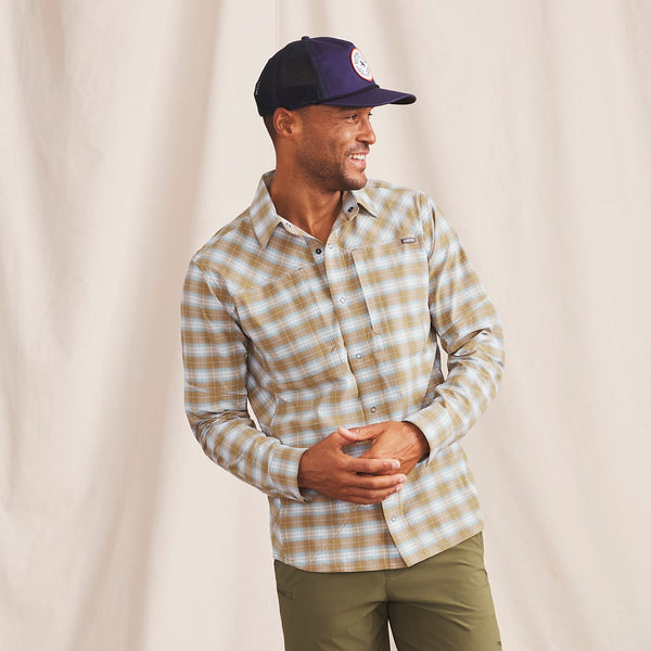 Man smiling wearing beige and white checkered shirt and blue fishing cap