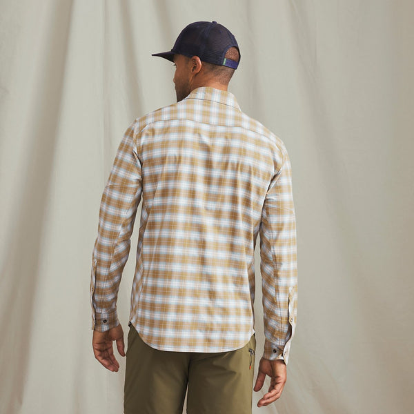 Man with his back to the camera wearing beige and white checkered shirt and black cap in front of beige background