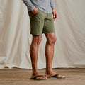 lowerb body of man wearing flip flops and dark green shorts