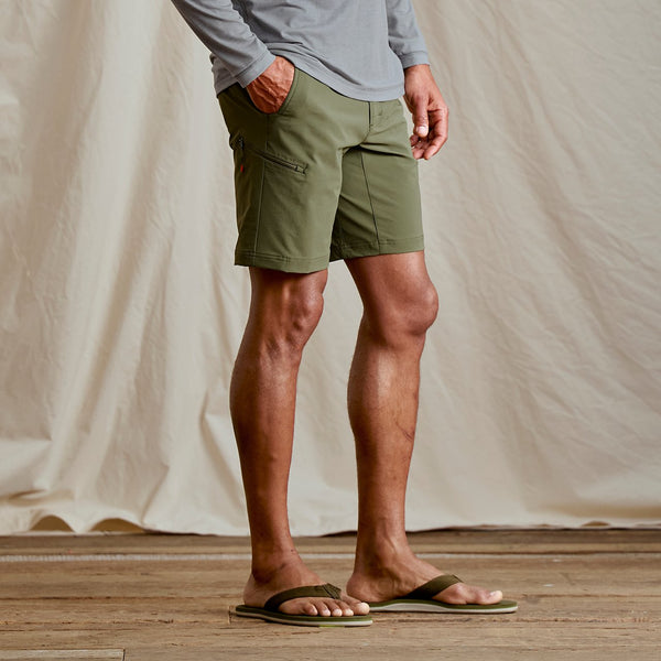 lowerb body of man wearing flip flops and dark green shorts