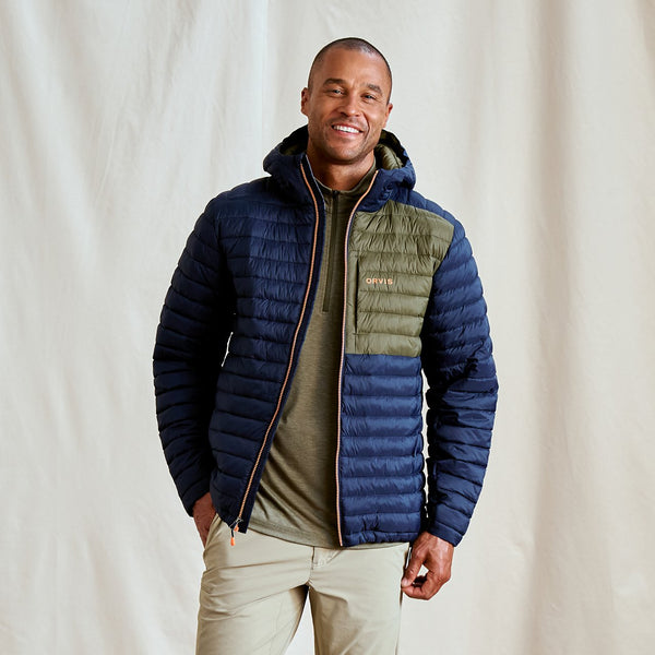 man smiling to camera wearing blue jacket in front of green background