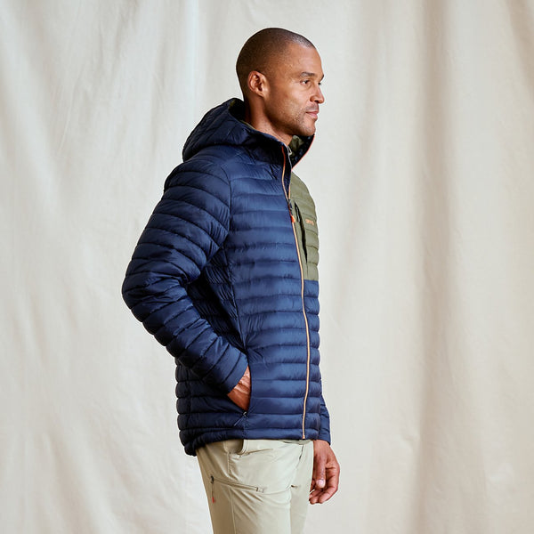 man wearing dark blue jacket and beige pants in front of beige background