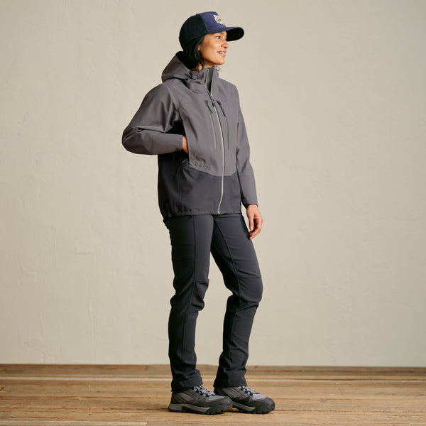 woman wearing dark blue cap, dark grey waterproof jacket and dark grey pants