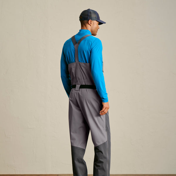 man wearing wadersm light blue sweater and fishing cap