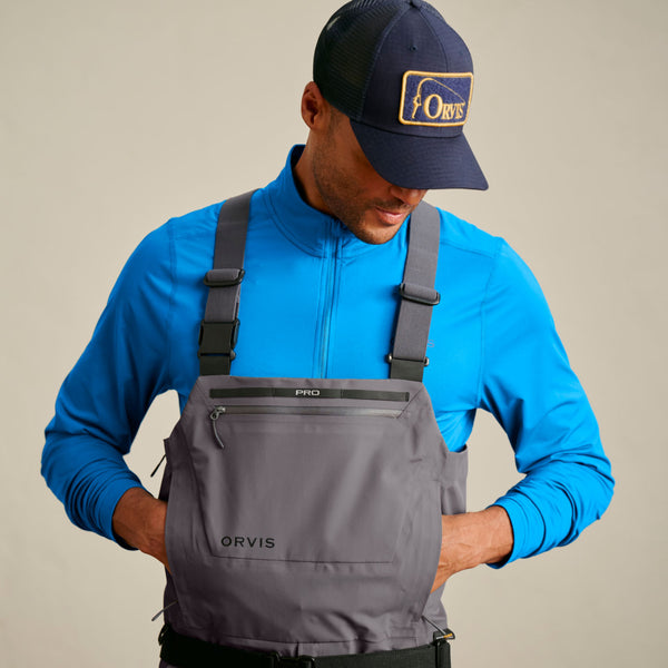man wearing blue half zipped shirt and dark grey waders