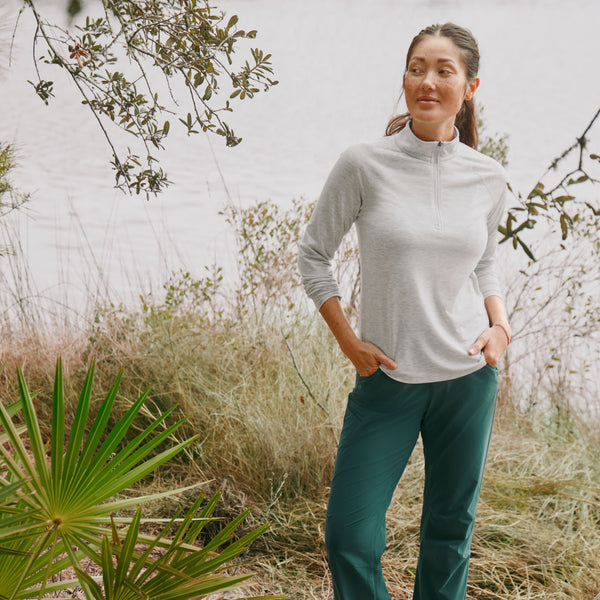 woman in the woods wearing half zipper sweater and green pants