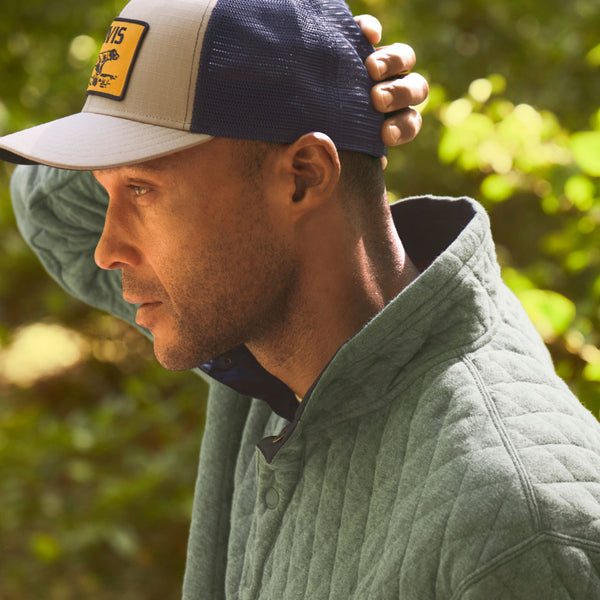 Man wearing green sweat er and dark blue cap