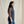 Load image into Gallery viewer, Woman wearing a blue vest over a plaid shirt with a beige background
