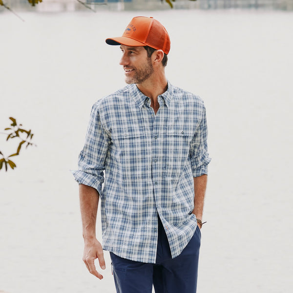 man wearing dark blue pants, blue and white shirt and orange cap