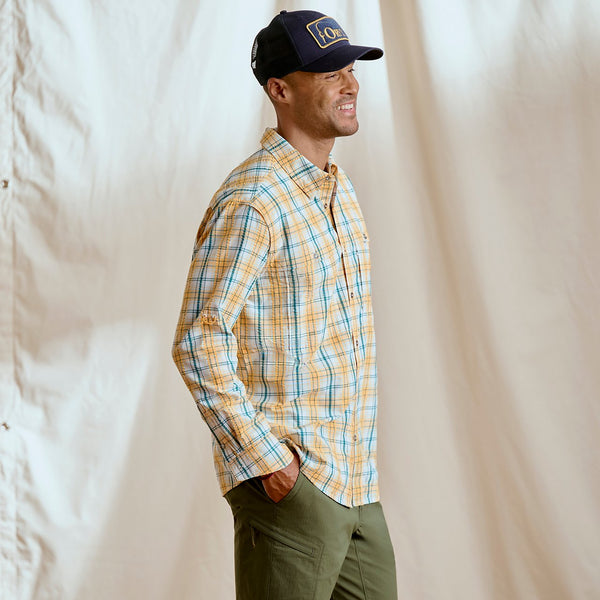 man smiling wearing checkered shirt and Orvis cap