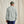 Load image into Gallery viewer, Man wearing a light grey long-sleeve shirt and blue pants against a beige background
