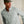 Load image into Gallery viewer, Man wearing a light grey shirt and green cap against a beige background
