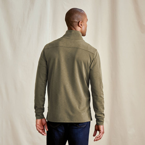Man wearing a green long-sleeve shirt against a beige background