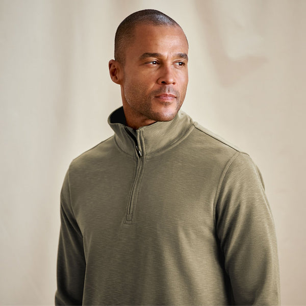 Man wearing a green pullover against a beige background