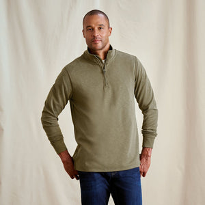Man wearing a green long-sleeve shirt with a quarter zip on a beige background