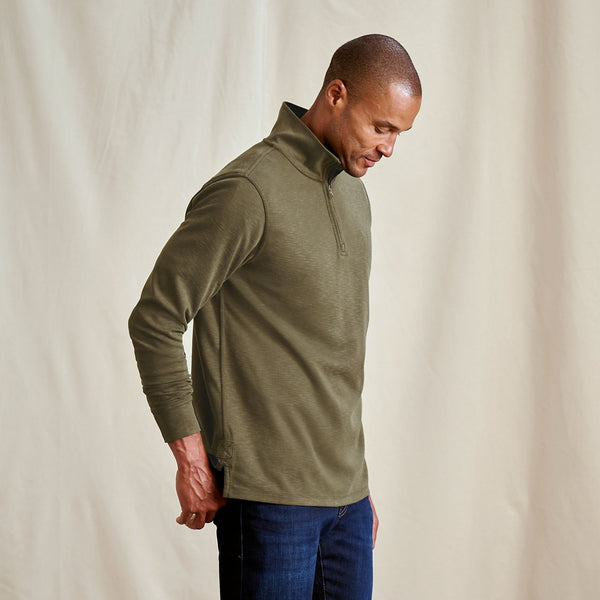 Man wearing a green pullover against a beige background
