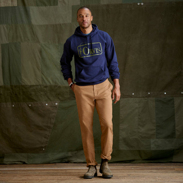 man wearing dark blue Orvis hoodie and brown trousers
