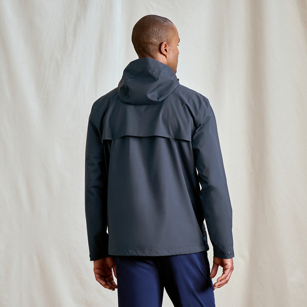 Person wearing a dark grey raincoat on a plain background