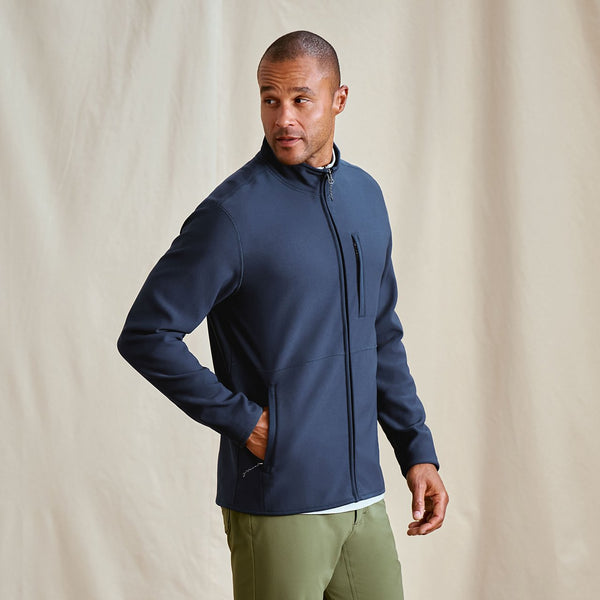 Man wearing a navy blue jacket against a beige background