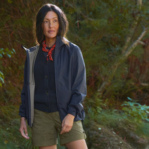 Woman standing in a forest wearing outdoor clothing