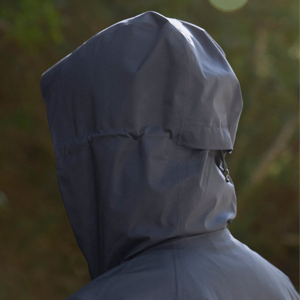 Person wearing a gray raincoat with hood in a natural setting