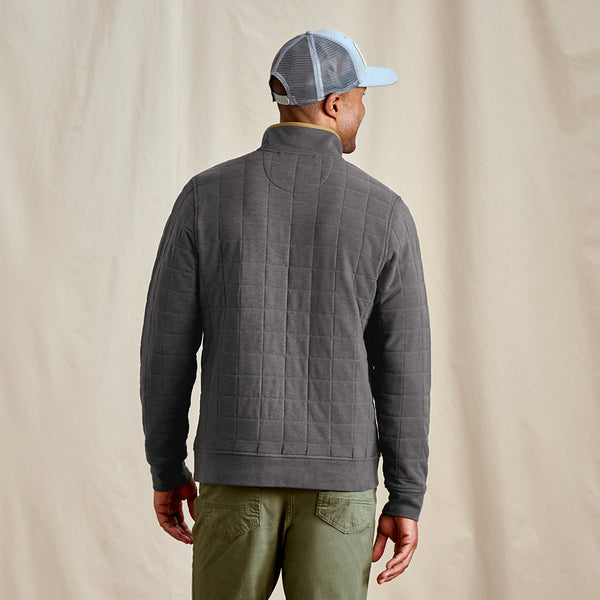Man wearing a grey quilted jumper and cap on a beige background
