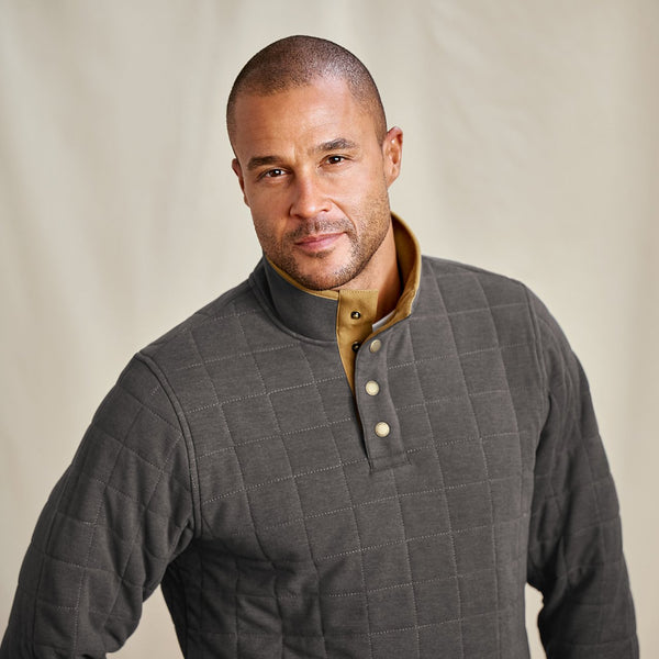 Man wearing a grey quilted jacket with a beige interior on a plain background