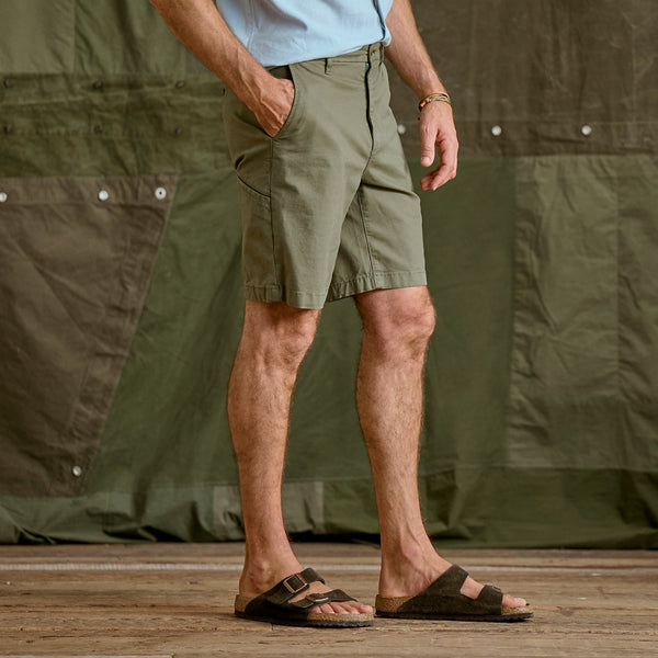 lower body of man wearing dark green shorts and blue shirt