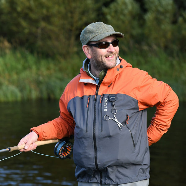 man smiling wearing Orvis fly fishing jacket and sunglasses