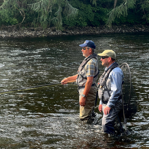 two men wading in river