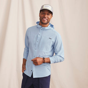 man wearing light blue waterproof jacket and cap smiling to the camera