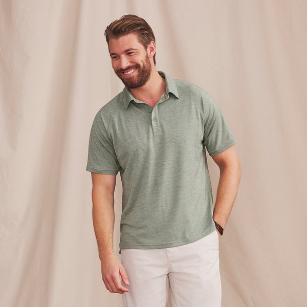 man smiling waering green poloshirt and white trousers