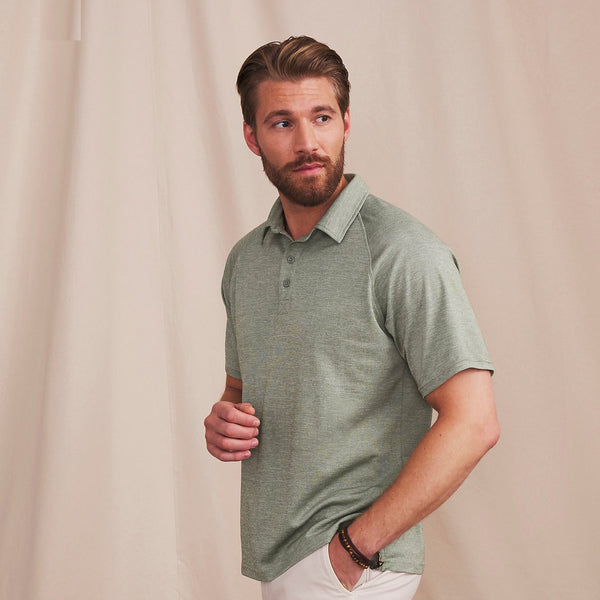 man wearing green poloshirt in front of beige background