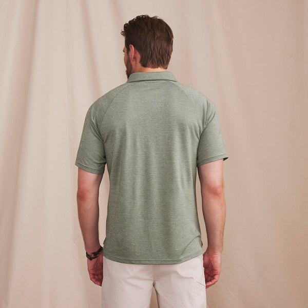man with his back to the camera wearing green polo shirt and white trousers