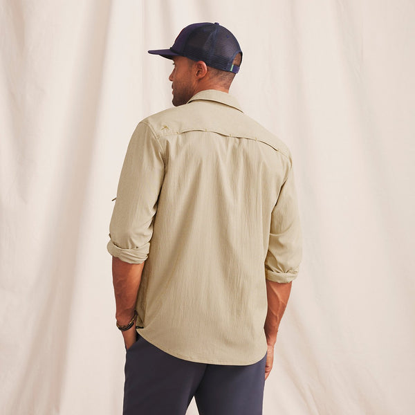 man with his back to the camera in front of beige background