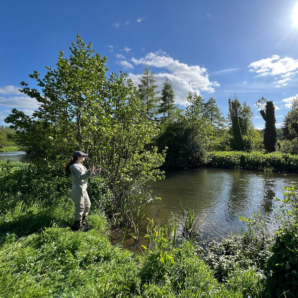 woman on river bank fly fishing