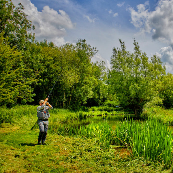 woman on the riverbank fly fishing