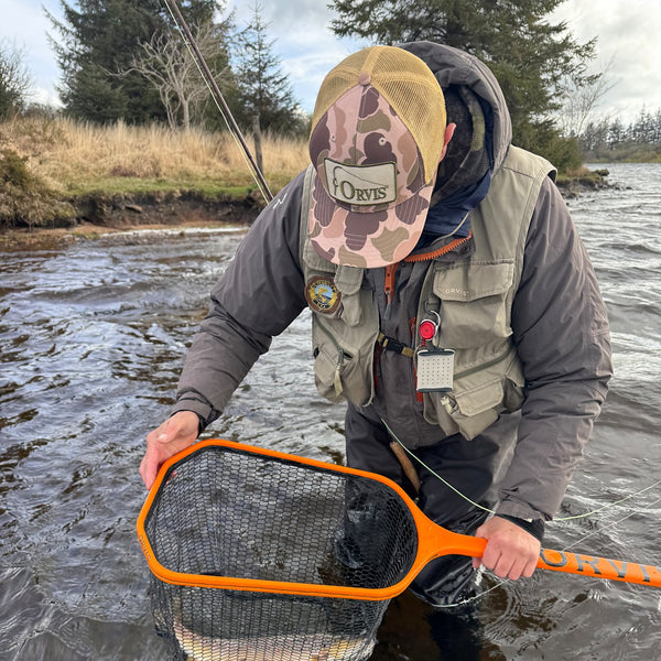 man in riverbank with fish in fish net