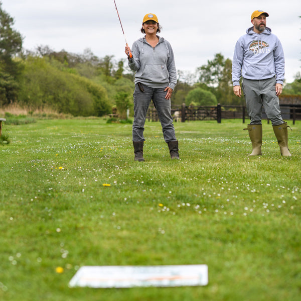 man and woman practising fly casting on grass