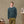 Load image into Gallery viewer, A man wearing a dark teal knit sweater and olive green trousers stands in a studio setting with an easel and painting desk visible in the background.
