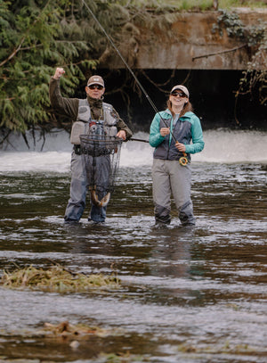 man and woman fly fishing in river