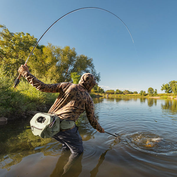 man reeling in fish in the river