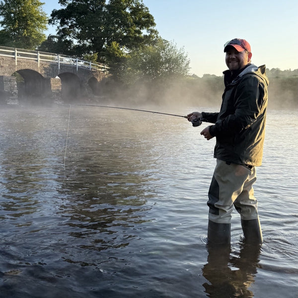 man fly fishing and smiling to camera
